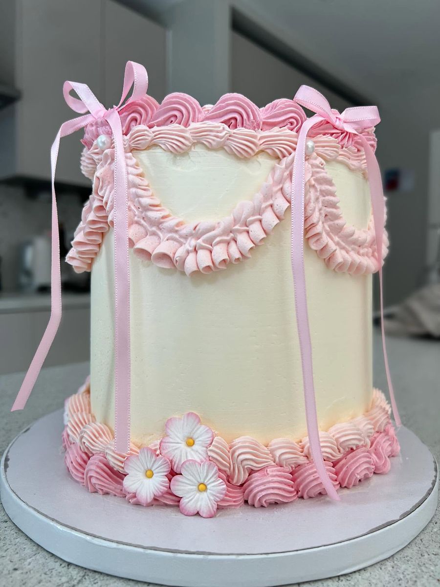 Pink vintage cake by Just In Cakes Co. Hand piped vintage frills with pink ribbon bows.