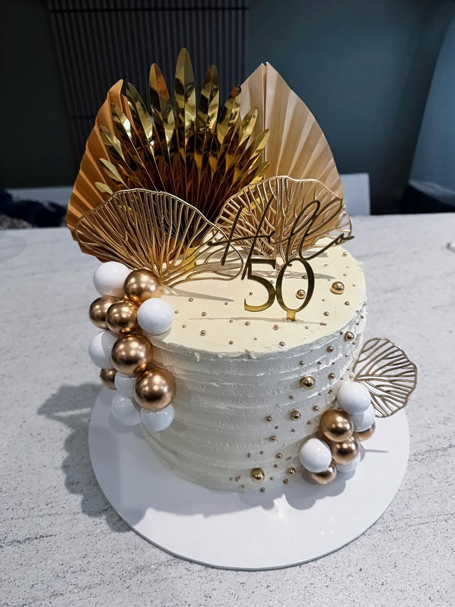 Gold 50th cake by Just In Cakes Co. Textured buttercream with gold sails and pearls.