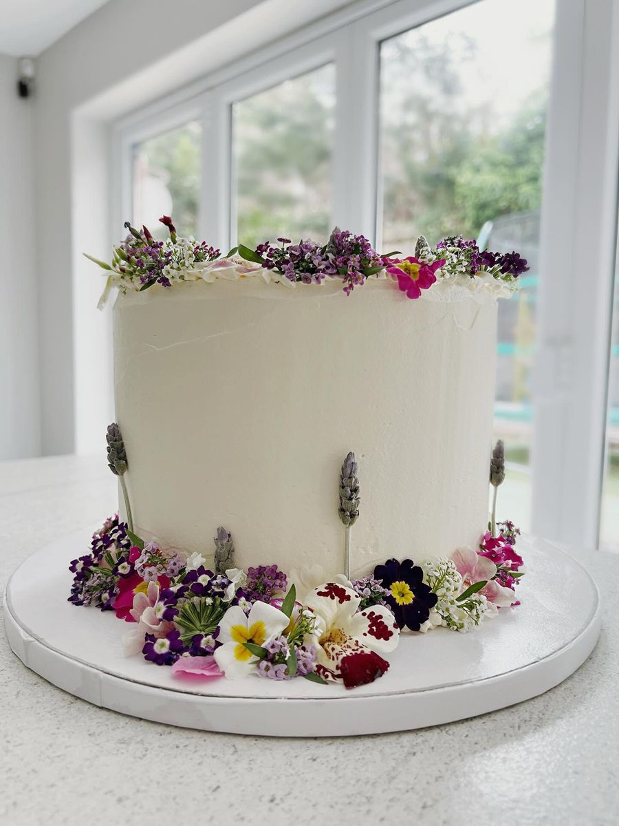 Fresh edible flowers cake by Just In Cakes Co. Smooth white buttercream dressed with fresh edible flowers.