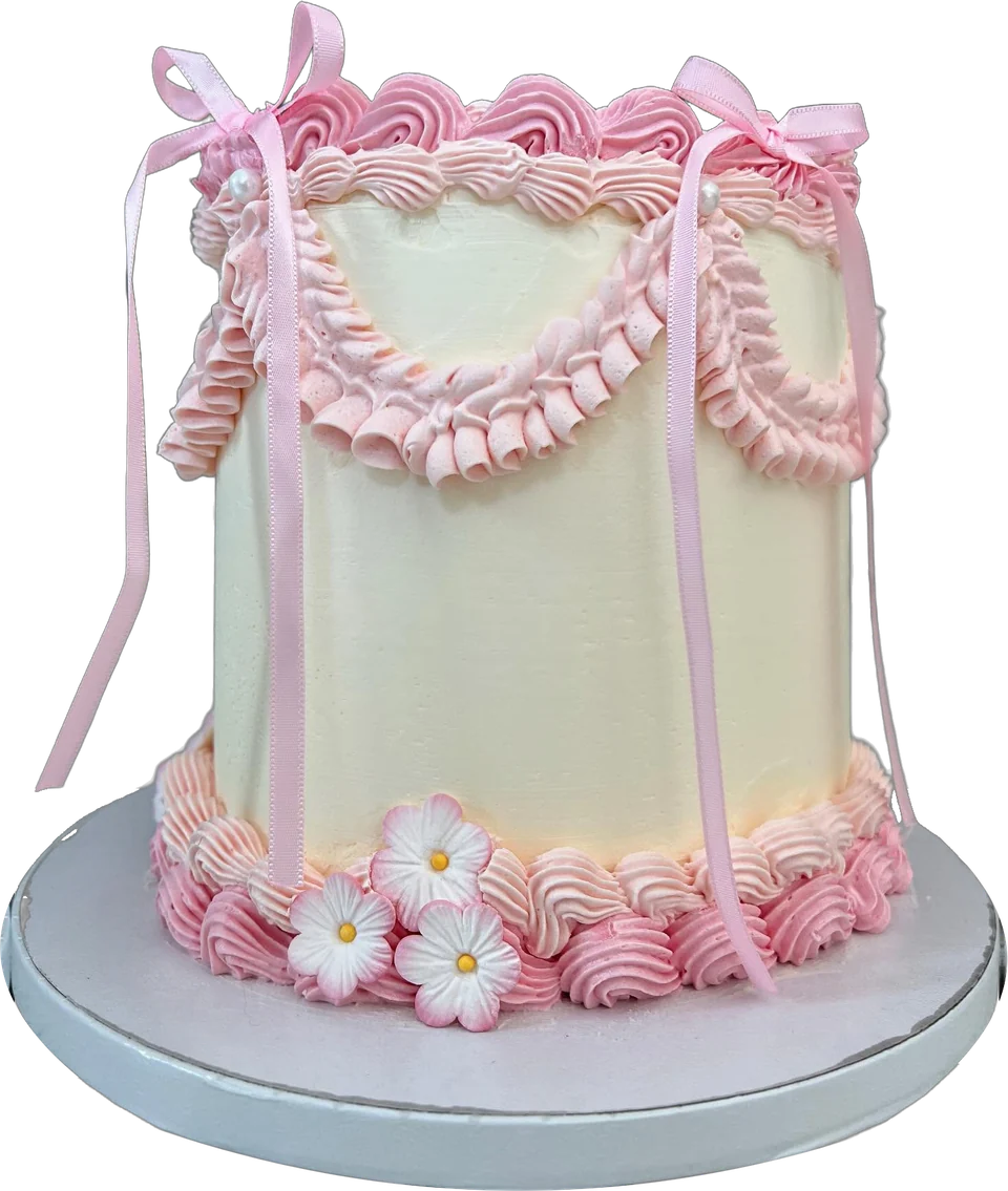 One of our vintage celebration cakes: ivory buttercream with pink piped frills, ribbon bows and sugar flowers