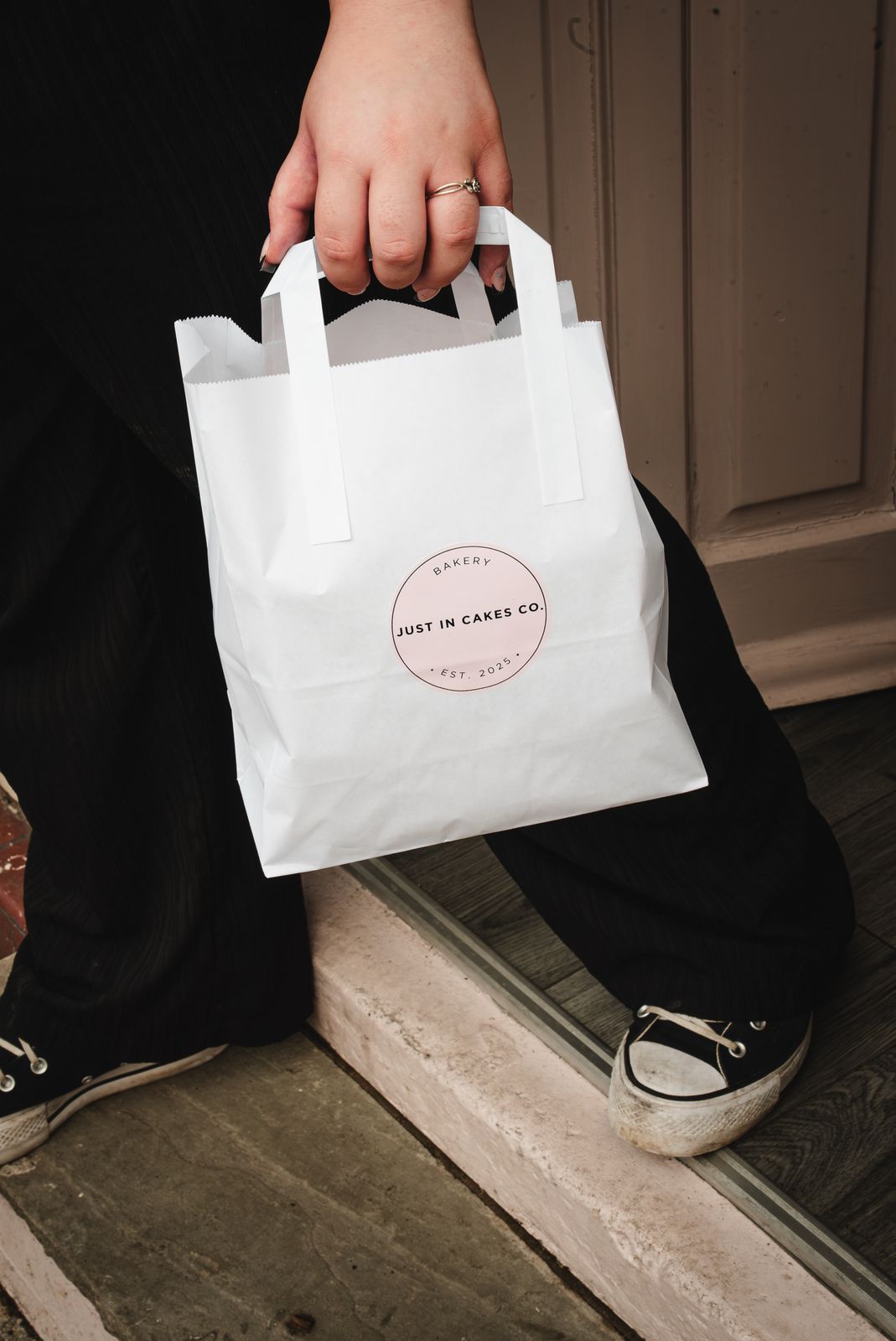 A customer carrying a Just In Cakes Co. paper bag